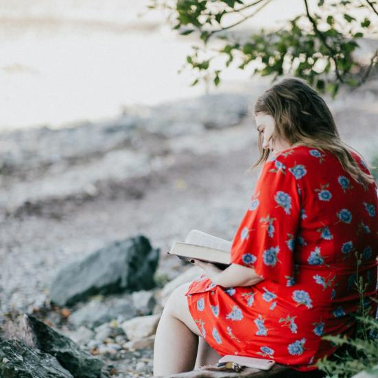 Naturdigte: en kvinde læser ved en strand. Fotokreditering: Priscilla Du Prezz for Unsplash.