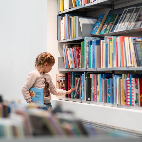 Et barn kigger på bøger på biblioteket. Fotokreditering: Christopher Egeberg for Centralbiblioteket.