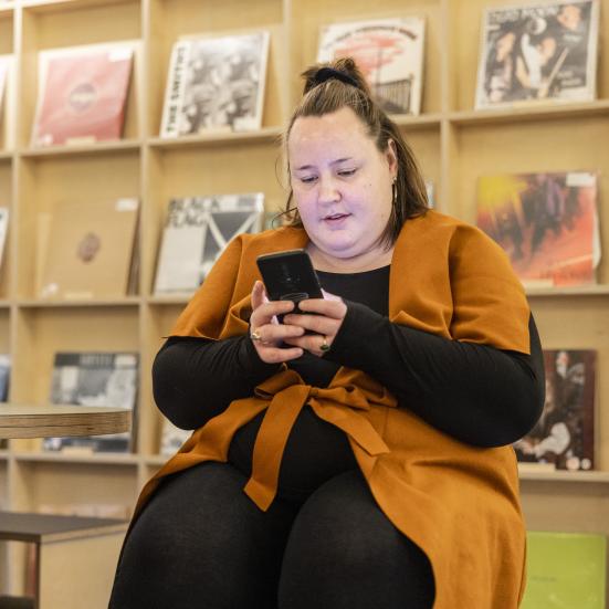 Kvinde bruger sin telefon på biblioteket. Fotograf: Nikolai Linares for Centralbiblioteket.