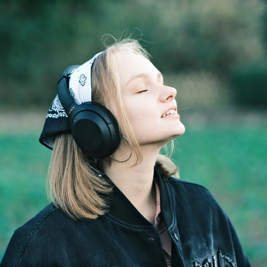 En kvinde lytter til podcast i naturen. Fotokreditering: Hongwei FAN for UnSplash.