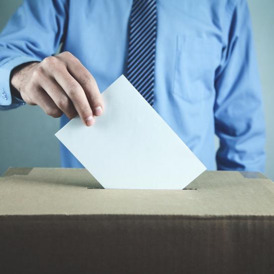 En stemmeseddel bliver puttet i en stemmeurne