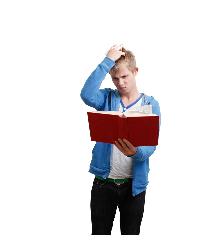 Foto af ung mand, der ser ud til at have svært ved at læse i en bog, som han står med i hånden