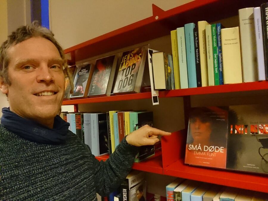 Foto af Thomas Damholt, der peger på bogen: Små døde på Glumsø Bibliotek