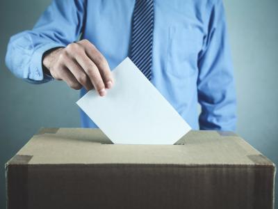 En stemmeseddel bliver puttet i en stemmeurne