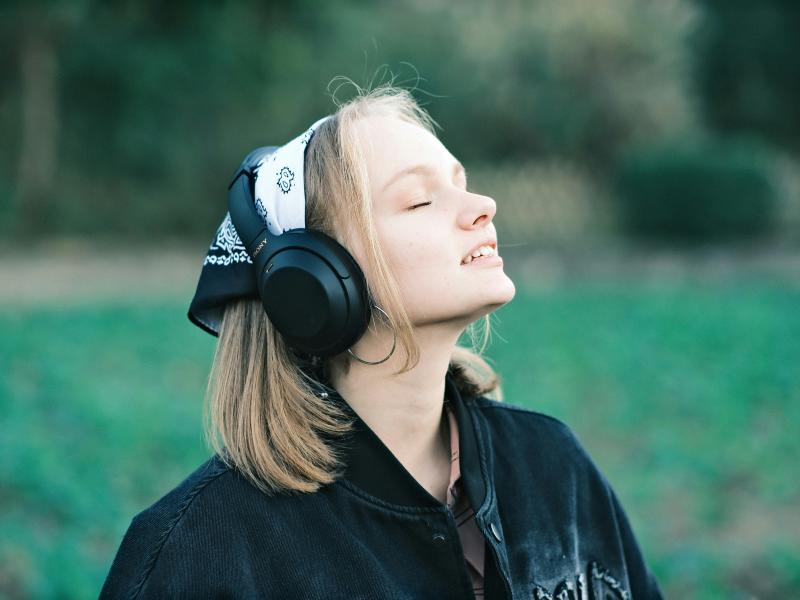 En kvinde lytter til podcast i naturen. Fotokreditering: Hongwei FAN for UnSplash.